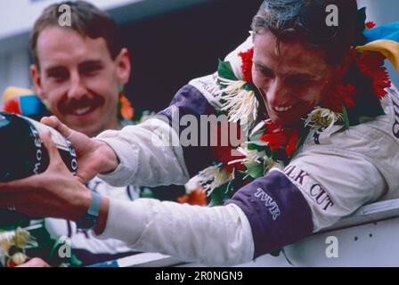 Rennfahrer des Jaguar XJ220 Rennsportteams, der Champagner auf der italienischen GT Monza, Italien 1993, einschenkt Stockfoto