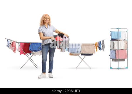 Ganzlängenporträt einer erwachsenen Frau, die einen Wäschekorb vor Waschlinien hält, isoliert auf weißem Hintergrund Stockfoto