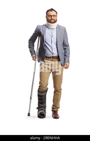 Das Gesamtporträt eines Mannes mit Halskragen und orthopädischem Stiefel, der mit einer isolierten Krücke auf weißem Hintergrund steht Stockfoto