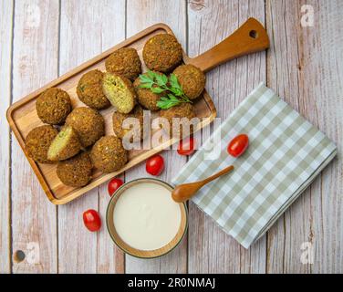 Falafel-Kugeln auf einem Holzbrett und Tahini-Sauce Stockfoto