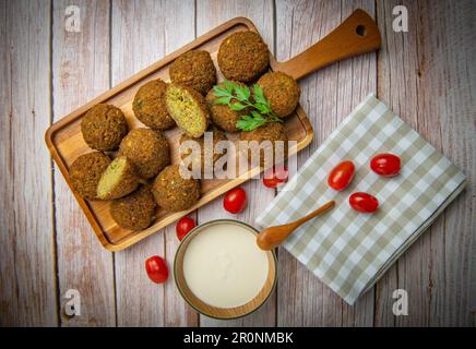 Falafel-Kugeln auf einem Holzbrett und Tahini-Sauce Stockfoto
