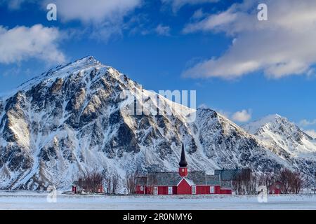 Rote Holzkirche von Flakstad mit schneebedeckten Bergen im Hintergrund, Lofoten, Nordland, Norwegen Stockfoto