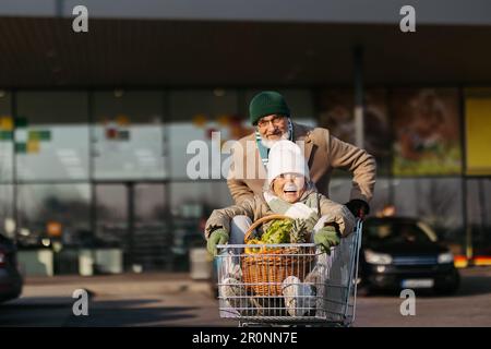 Seniorenpaar, das aus dem Supermarkt nach Hause geht und Spaß hat. Stockfoto
