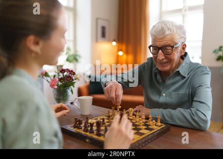Ein älterer Mann, der mit seiner Enkelin Schach spielt. Stockfoto