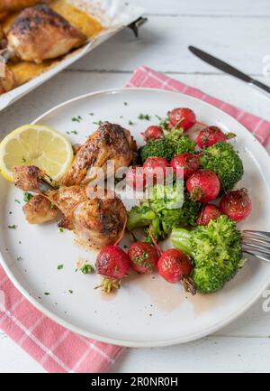 Warmer Salat mit rotem Rettich und Brokkoli. Serviert mit gebackenem Hähnchen auf einem Teller Stockfoto