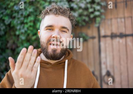 Ein hübscher, lockiger Mann nimmt ein Video von sich auf - Video-Blog und Jugend-Blogger-Konzept Stockfoto