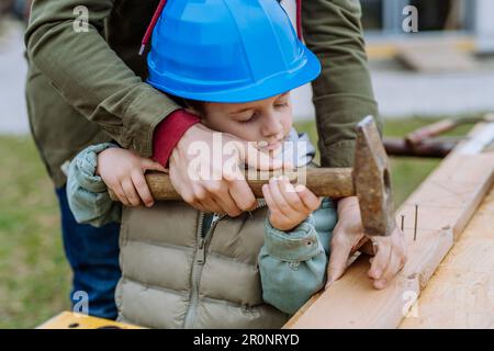 Nahaufnahme von Vater und seinem kleinen Sohn, die draußen mit Holz arbeiten. Stockfoto