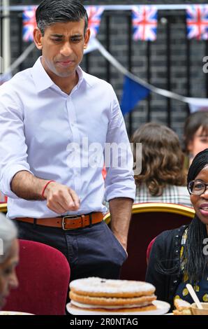 Premierminister Rishi Sunak zeigte ungewiss auf einen Kuchen während des großen Mittagessens der Krönung, das von ihm und seiner Frau Akshata Murty in der Downing Street veranstaltet wurde. Stockfoto