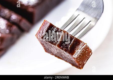 Ein Stück Guava-Konfitüre auf einer Gabel. Verschwommene Guave im Hintergrund. Platz für Text, süß aus Obst, traditionell der Juni-Festlichkeiten in Brasilien, r Stockfoto