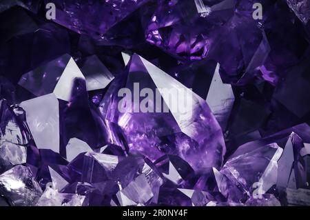 Amehtystischer violetter Kristall auf schwarzem Hintergrund. Texturhintergrund für Makrodetails. Nahaufnahme von rohem, unpoliertem Halbedelstein Stockfoto