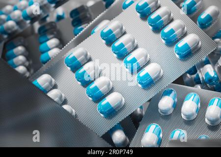 Blaue und weiße Pillen in Blisterpackungen auf einem Haufen. Selektiver Fokus... Pharmazie und pharmazeutische Industrie oder Ubermedikationskonzept. Stockfoto