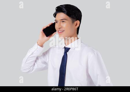 Porträtieren Sie einen jungen asiatischen Geschäftsmann, der ein Smartphone benutzt, isoliert auf weißem Hintergrund spricht, einen Geschäftsmann, der steht und mit dem Smartphone vertrauter spricht Stockfoto