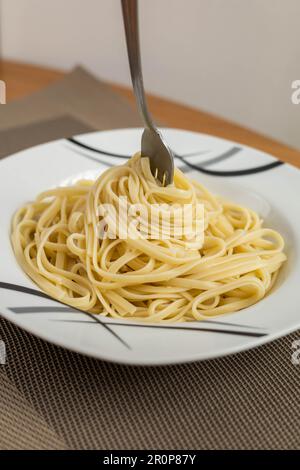 Hausgemachte Speiseplatte mit Spaghetti mit Gabel, Dekoration und Hausleben, Lebensmittelzubereitung, Hintergrund Stockfoto