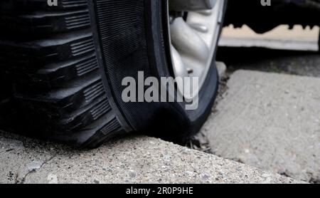 Ein defekter Reifen wurde aufgrund eines schlechten Parkplatzes auf den Bordstein gedrückt Stockfoto