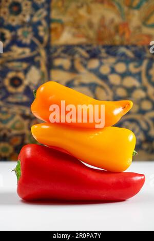 Drei kleine Paprika, eine rote, eine gelbe und eine orangefarbene, übereinander angeordnet. Stockfoto