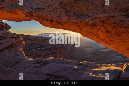Sonnenaufgang über den La Sal Mountains durch den Mesa Arch im Canyonlands National Park bei Moab, Utah. Stockfoto