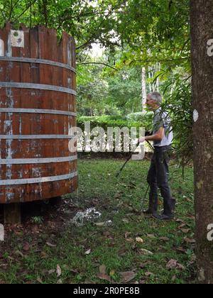 PUNTA GORDA, TOLEDO, BELIZE - 1. NOVEMBER 2012 Mann, der einen alten traditionellen Wassertank im Dschungel mit einem Hochdruckreiniger reinigte ( Stockfoto