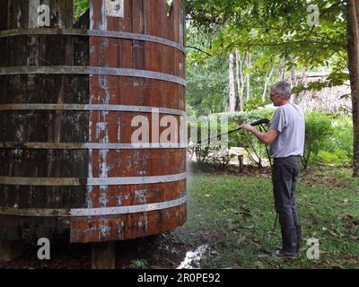 PUNTA GORDA, TOLEDO, BELIZE - 1. NOVEMBER 2012 Mann, der einen alten traditionellen Wassertank im Dschungel mit einem Hochdruckreiniger reinigte ( Stockfoto