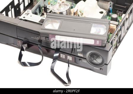 Zerlegte Videorekorder mit zerbrochener VHS-Kassette im Retro-Look, abgewickeltes Band isoliert auf weißem Hintergrund. Stockfoto