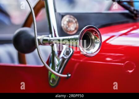 Glänzendes Stahlhorn auf rotem Oldtimer, Nahaufnahme Detail, nur Metallfelge im Fokus Stockfoto