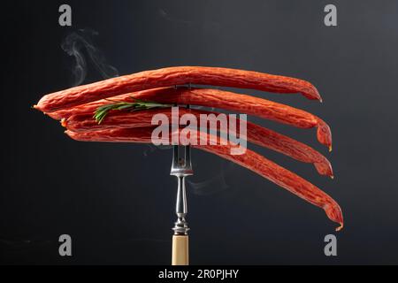 Gesmokte Würstchen mit Rosmarin auf schwarzem Hintergrund. Stockfoto