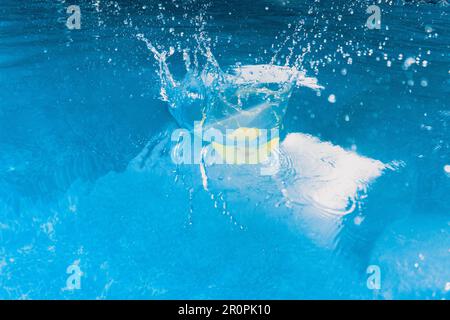 Gelbe Gummiente, die mit einem großen Spritzer in das Wasser des Schwimmbeckens taucht Stockfoto