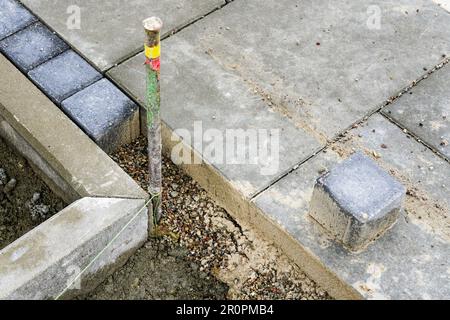 Baustellenfragment eines neuen unvollendeten Gehwegs, Betonpflastersteine und Platten unterschiedlicher Grösse Stockfoto