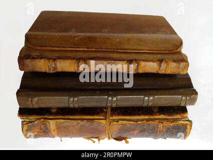 Sammlung von drei alten Büchern auf weißem Hintergrund. Das Cover dieser Bücher besteht aus Leder oder Leder und Holz. Stockfoto