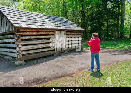 Cades Cove, Tennessee, USA – 24. April 2023: Horizontale Aufnahme eines Touristen, der eine Pionierhütte in Cades Cove im Frühling fotografiert. Stockfoto