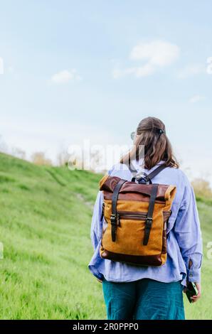 Rückansicht einer Frau im Leinenkostüm mit Rucksack, die einen Hügel hinaufgeht Stockfoto