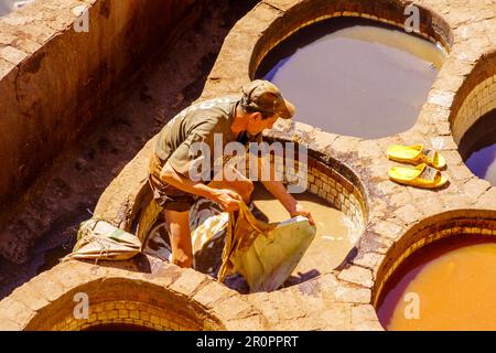 Fes, Marokko - 31. März 2023: Szene der Ledergerberei mit Arbeitern und Steinfässern in verschiedenen Farben. Fes, Marokko Stockfoto