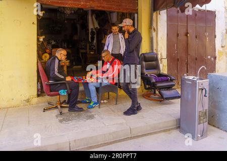 Fes, Marokko - 31. März 2023: Blick auf eine Gasse mit Einheimischen, die Backgammon spielen, in Fes, Marokko Stockfoto