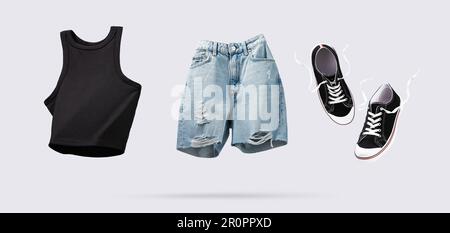 Trendiges Tanktop aus fliegender Baumwolle, Blue Jeans Shorts und Turnschuhe isoliert auf grauem Hintergrund. Reinigen Sie den schwarzen Erntegutverdeck. Branding-Kleidung. Ein Modell für deinen de Stockfoto