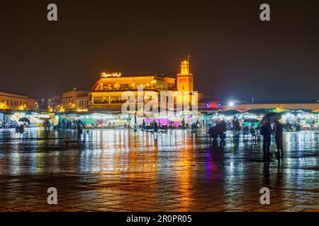 Marrakesch, Marokko - 04. April 2023: Regnerische Nachtszene auf dem Platz Jemaa el-Fnaa mit verschiedenen Verkaufsständen, Einheimischen und Besuchern in Marrakesch, Marokko Stockfoto