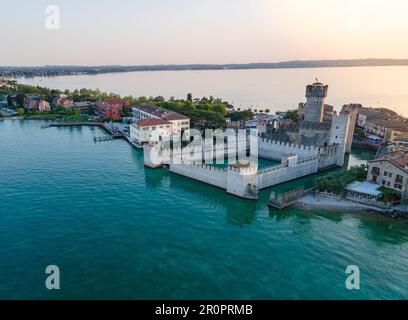 Die mittelalterliche Stadt Sirmione und ihre wunderschöne Burg in der Nähe des Gardasees in Italien bei Sonnenuntergang aus der Vogelperspektive Stockfoto