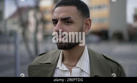 Ein nachdenklicher junger Araber steht draußen in der Stadtstraße. Hübscher Mann aus dem Nahen Osten, Porträt, Nahaufnahme Stockfoto