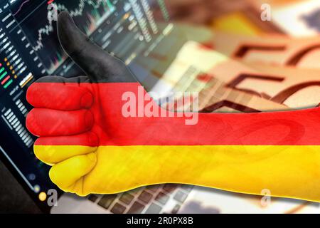 Wirtschaftsdiagramm: Daumen hoch mit der deutschen Flagge, den Börsenindikatoren und den Euro-Bargeld-Banknoten (Geld, Inflation, Erfolg, Märkte, Finanzen, Unternehmen) Stockfoto