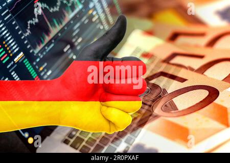 Wirtschaftsdiagramm: Daumen hoch mit der deutschen Flagge, den Börsenindikatoren und den Euro-Bargeld-Banknoten (Geld, Inflation, Erfolg, Märkte, Finanzen, Unternehmen) Stockfoto