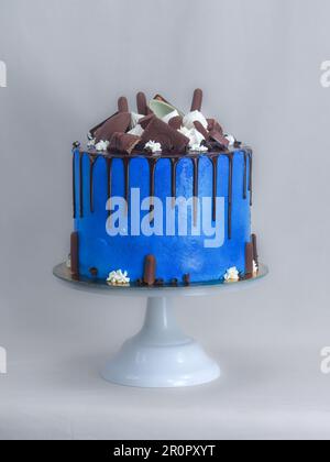 Makro mit blauem Frostguss und dunklem Schokoladenglasur und gemischten Süßigkeiten, isoliert auf weißem Hintergrund zum Feiern Stockfoto