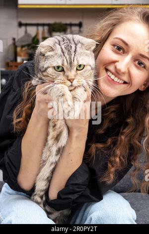 Junge lächelnde Frau, die ihre schottische Rasse in der Hand hält. Stockfoto