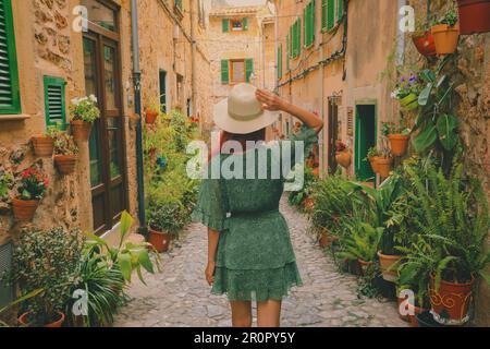 Weicher Fokus auf Frauen in grüner Kleiderfarbe, die in charmanten Straßen mit Töpfen und Pflanzen im Dorf Valldemossa, Mallorca, stehen Stockfoto