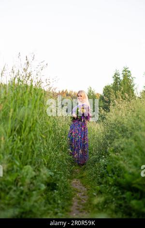 Porträt eines Mädchens in einem blühenden Feld in der Sonne bei Sonnenuntergang Stockfoto