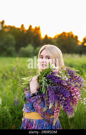 Porträt eines Mädchens in einem blühenden Feld in der Sonne bei Sonnenuntergang Stockfoto