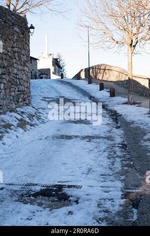 Verschneite kopfsteingepflasterte Straße mit Eis und Schnee in einer Winterlandschaft in Bellver de Cerdanya Stockfoto