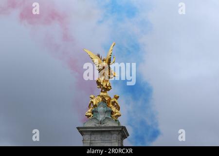 Rote, weiße und blaue Rauchpfade, die von der RAF hinterlassen wurden Rote Pfeile markieren die Krönung, die hinter dem Victoria Monument zu sehen ist Stockfoto