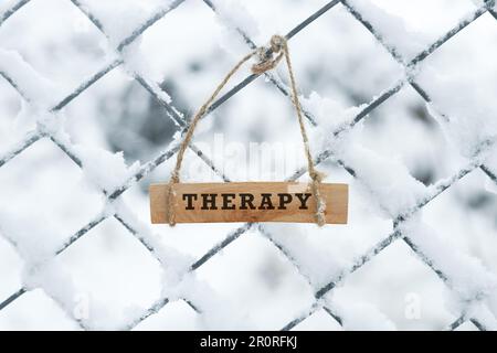 Die Inscription Therapy ist auf einer Holzfläche beschriftet. Kaltes Wetter im Freien. Stockfoto