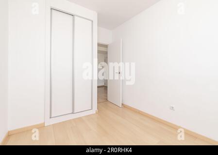 Ein leeres Zimmer in einem Apartment mit eingebautem Kleiderschrank mit weißen Schiebetüren Stockfoto