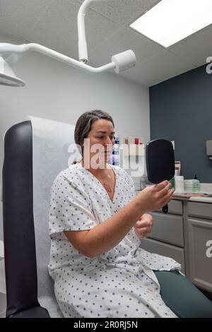 Junge 30s-Dermatologie-Patientin untersucht mögliche Exzisionsstelle eines Basalzellkarzinoms auf der weiblichen Brust. Stockfoto