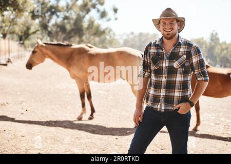 Ich liebte es immer, von Tieren umgeben zu sein. Porträt eines Bauern auf einer Ranch mit Pferden im Hintergrund. Stockfoto