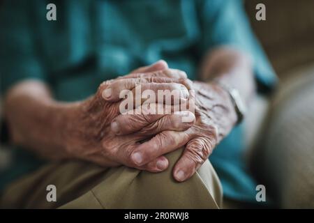 Hände erzählen wirklich eine Geschichte. Ein nicht wiedererkennbarer Senior-Mann, der drinnen sitzt. Stockfoto